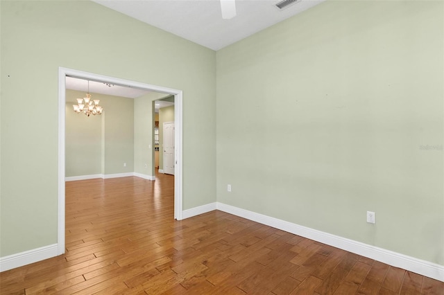 spare room featuring hardwood / wood-style flooring and ceiling fan with notable chandelier