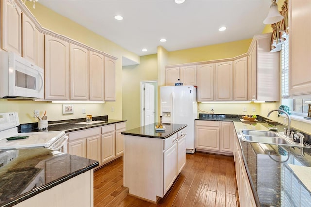 kitchen with sink, white appliances, hardwood / wood-style flooring, and a kitchen island