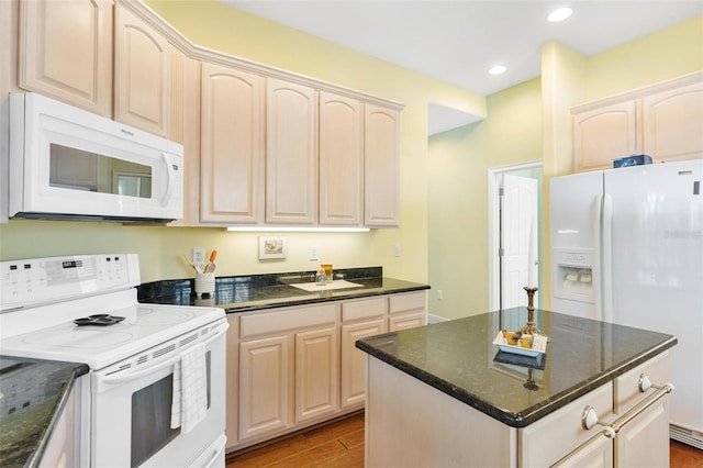 kitchen featuring dark stone countertops, white appliances, light hardwood / wood-style flooring, and a kitchen island