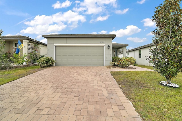 single story home featuring a garage and a front lawn