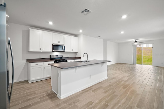 kitchen with white cabinets, an island with sink, stainless steel appliances, and sink