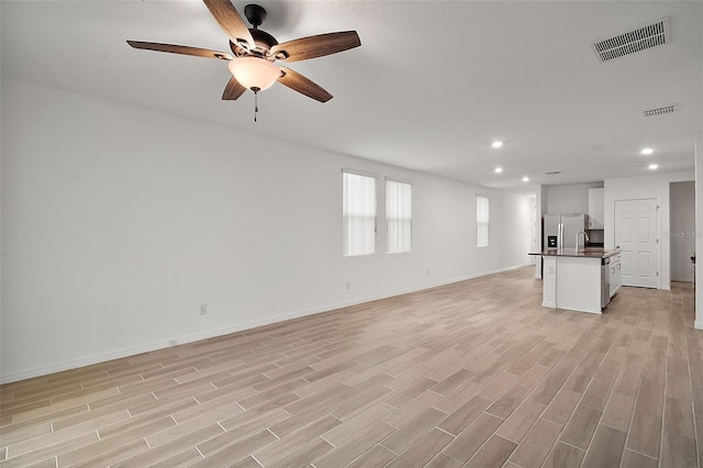 unfurnished living room with sink and light hardwood / wood-style flooring