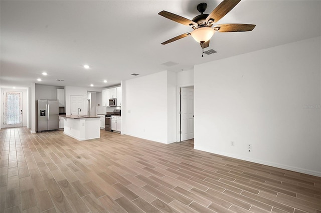 unfurnished living room featuring ceiling fan, light hardwood / wood-style flooring, and sink