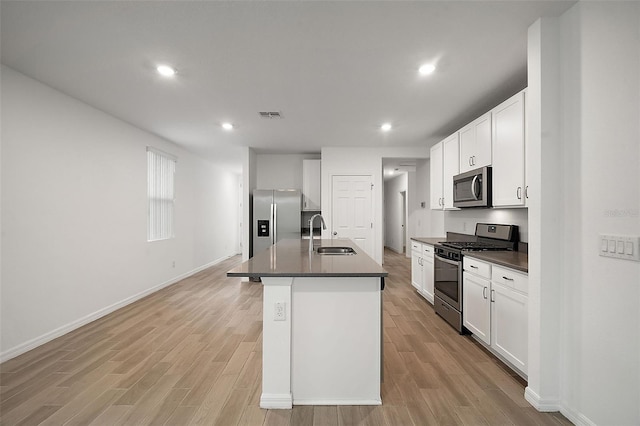 kitchen featuring white cabinets, appliances with stainless steel finishes, an island with sink, and sink