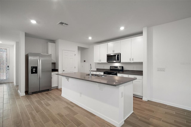 kitchen with a kitchen island with sink, white cabinetry, sink, and appliances with stainless steel finishes