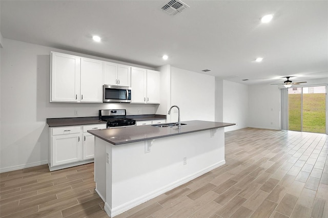 kitchen with white cabinets, stainless steel appliances, a kitchen island with sink, and sink