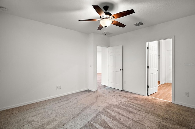 unfurnished bedroom featuring a textured ceiling, light colored carpet, and ceiling fan