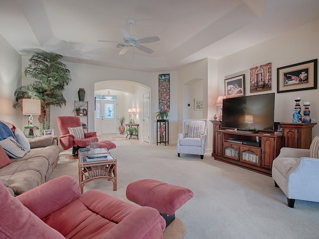 living room with ceiling fan, light colored carpet, and a raised ceiling