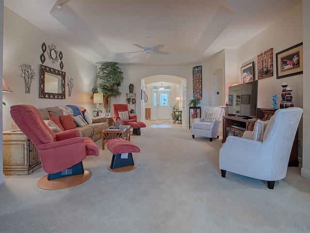 living room with ceiling fan, light colored carpet, and a raised ceiling