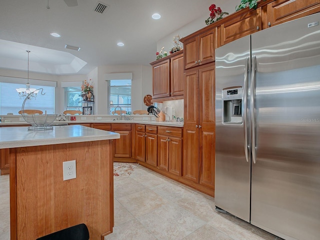 kitchen featuring decorative light fixtures, stainless steel fridge, a center island, and an inviting chandelier