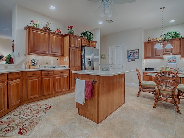 kitchen with stainless steel fridge with ice dispenser, backsplash, hanging light fixtures, ceiling fan with notable chandelier, and a center island