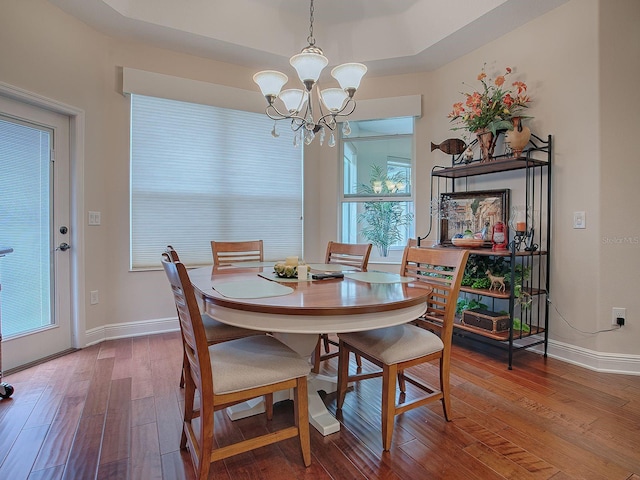 dining room with a wealth of natural light, an inviting chandelier, and hardwood / wood-style floors