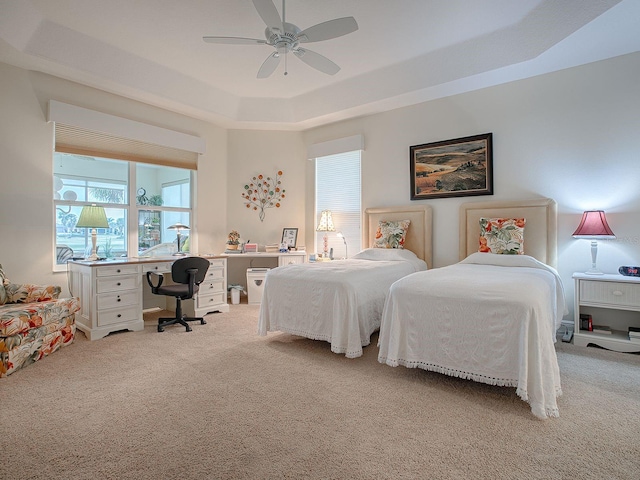 bedroom with ceiling fan, multiple windows, a tray ceiling, and light carpet