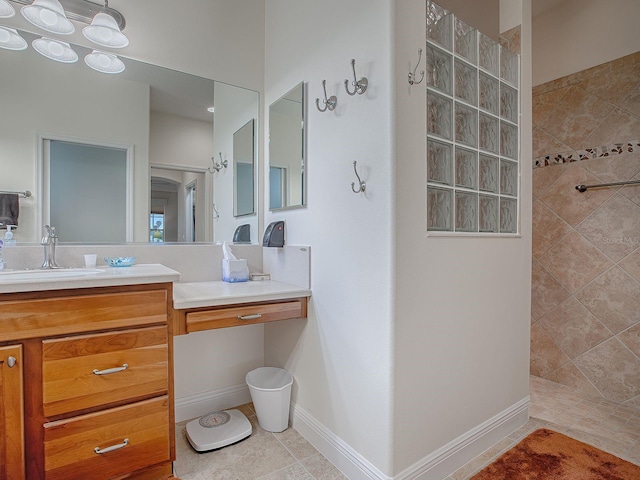 bathroom featuring tiled shower, vanity, and tile patterned flooring