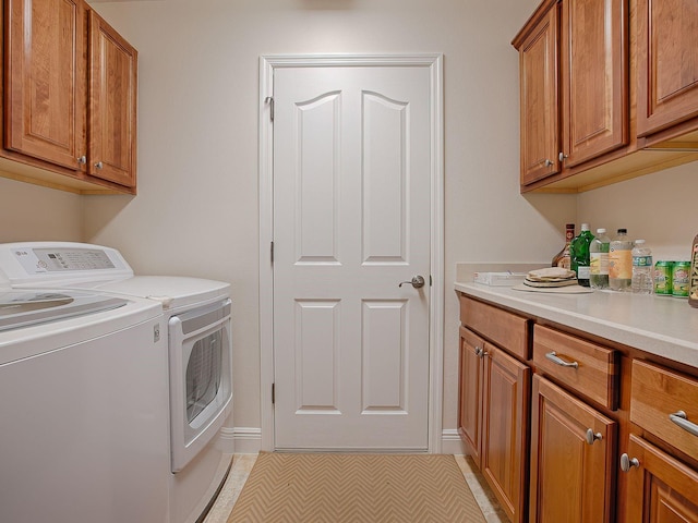 laundry area with cabinets, light tile patterned flooring, and washing machine and clothes dryer