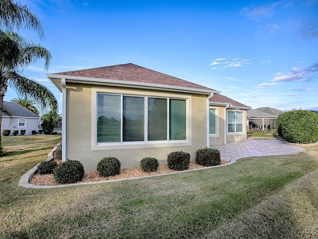 view of side of home featuring a patio area and a yard