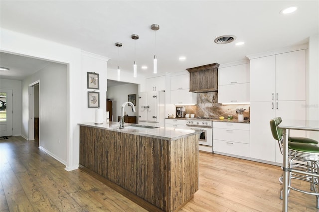 kitchen featuring sink, white cabinetry, high end range, dark brown cabinets, and pendant lighting