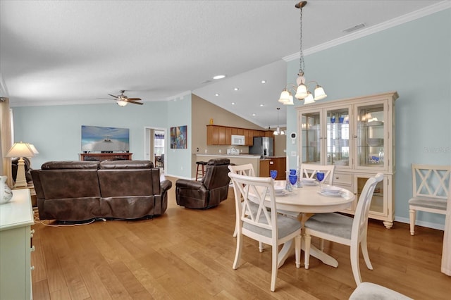 dining area with crown molding, light hardwood / wood-style flooring, ceiling fan with notable chandelier, and vaulted ceiling