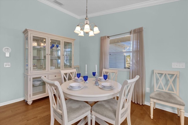 dining area with wood-type flooring, ornamental molding, and an inviting chandelier