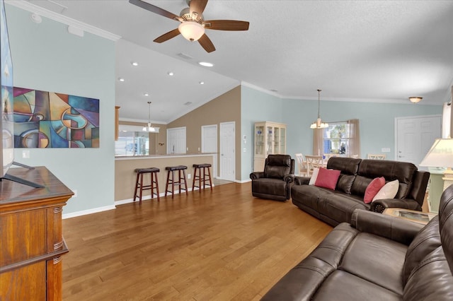 living room with hardwood / wood-style floors, ceiling fan, lofted ceiling, and crown molding