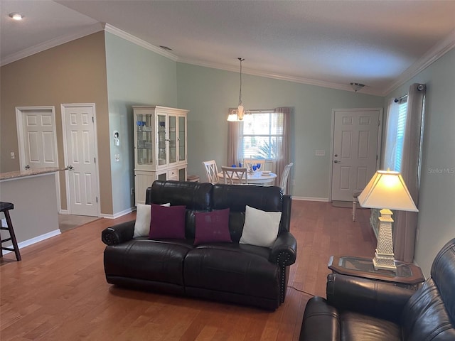 living area with lofted ceiling, baseboards, ornamental molding, and wood finished floors