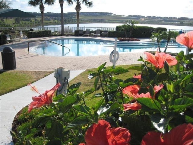 view of swimming pool featuring a patio and a water view