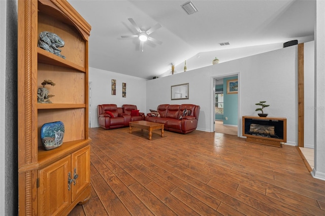 living area featuring dark wood-style floors, vaulted ceiling, a fireplace, and visible vents