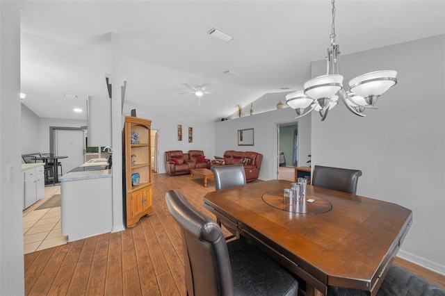 dining area with light wood-style floors, baseboards, vaulted ceiling, and ceiling fan with notable chandelier