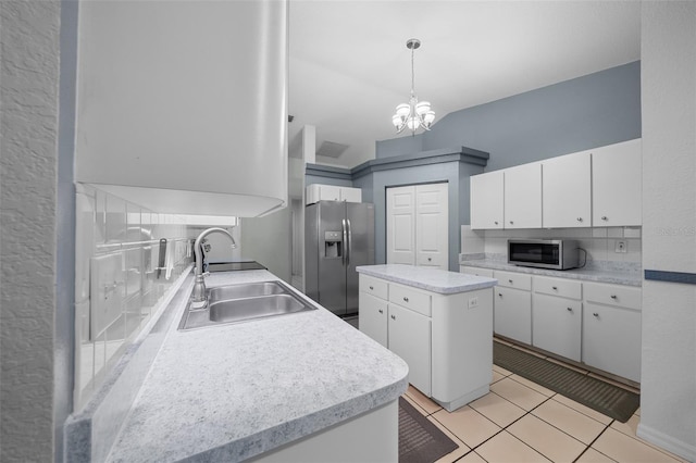 kitchen with light tile patterned floors, stainless steel appliances, light countertops, white cabinetry, and a sink