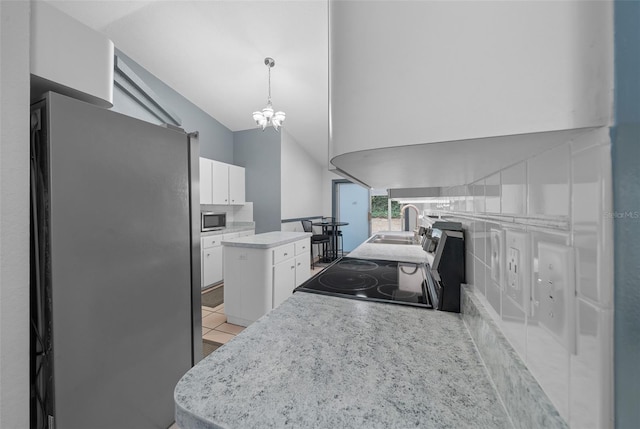 kitchen featuring vaulted ceiling, stainless steel appliances, light countertops, white cabinetry, and a sink