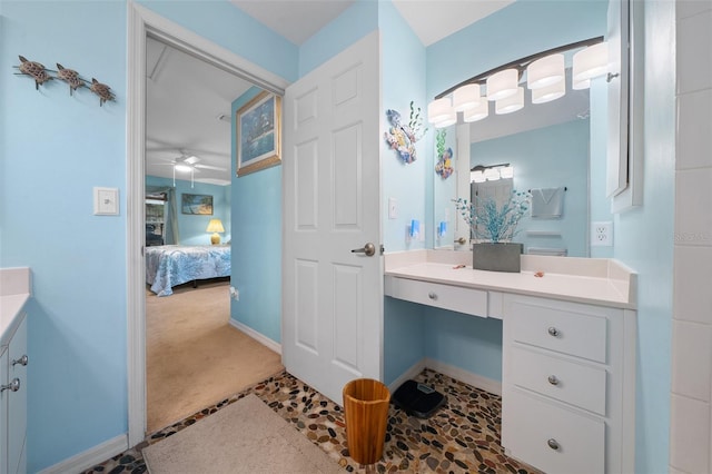 ensuite bathroom featuring a ceiling fan, connected bathroom, vanity, and baseboards