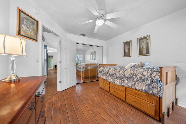 bedroom with dark wood-style floors, ceiling fan, visible vents, and a closet