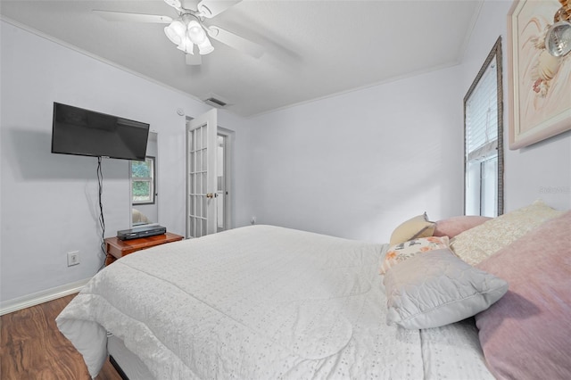 bedroom featuring ceiling fan, ornamental molding, wood finished floors, and visible vents