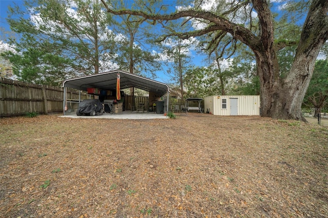 view of yard with an outbuilding, a storage shed, fence, and a detached carport