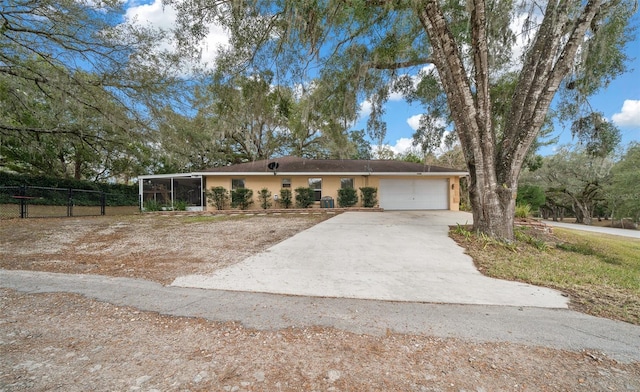 view of front facade featuring concrete driveway, a sunroom, an attached garage, fence, and stucco siding