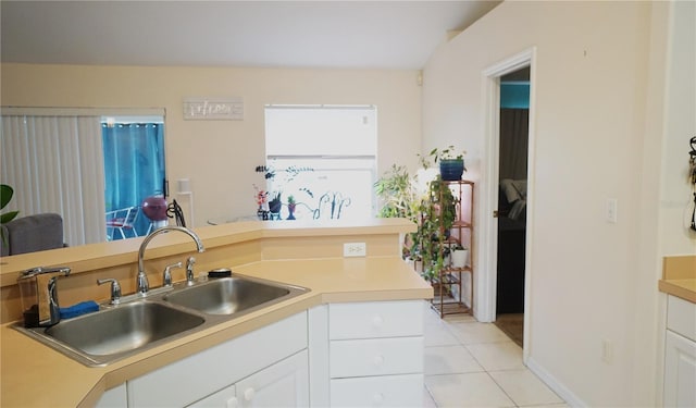 kitchen featuring sink, light tile patterned floors, and white cabinets