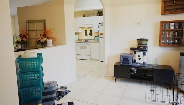 kitchen with light tile patterned floors, white cabinets, and white range with electric stovetop