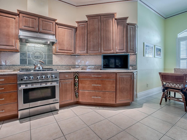 kitchen with backsplash, light tile patterned flooring, crown molding, and stainless steel stove