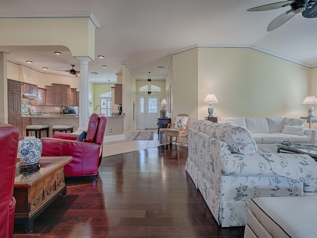 living room with decorative columns, dark hardwood / wood-style floors, crown molding, and ceiling fan