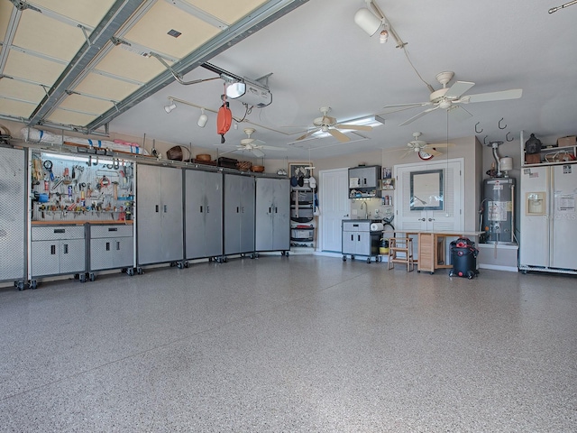 garage with ceiling fan, a garage door opener, gas water heater, a workshop area, and white fridge with ice dispenser