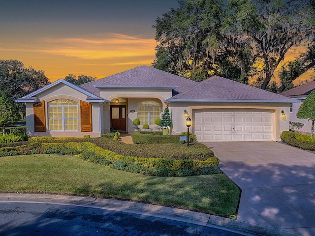 ranch-style home featuring a garage and a lawn