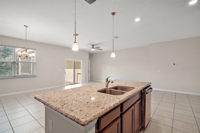 kitchen featuring sink, a center island with sink, light stone counters, light tile patterned flooring, and ceiling fan with notable chandelier