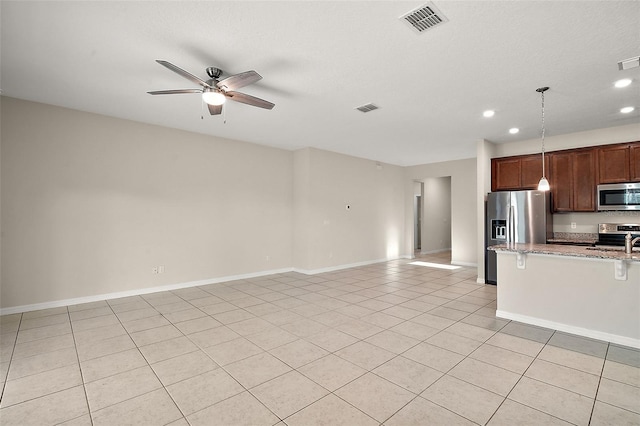 kitchen with light tile patterned floors, light stone countertops, ceiling fan, and appliances with stainless steel finishes