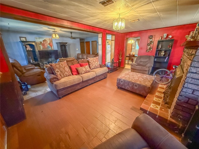 living room with a notable chandelier, a fireplace, and wood-type flooring