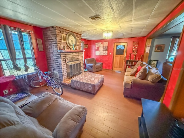 living room with a brick fireplace, a textured ceiling, and hardwood / wood-style floors