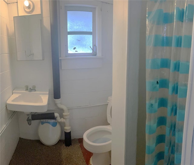 bathroom with a shower with shower curtain, sink, and toilet