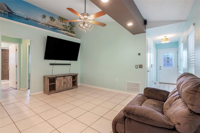 living room with ceiling fan, vaulted ceiling, a textured ceiling, and light tile patterned floors