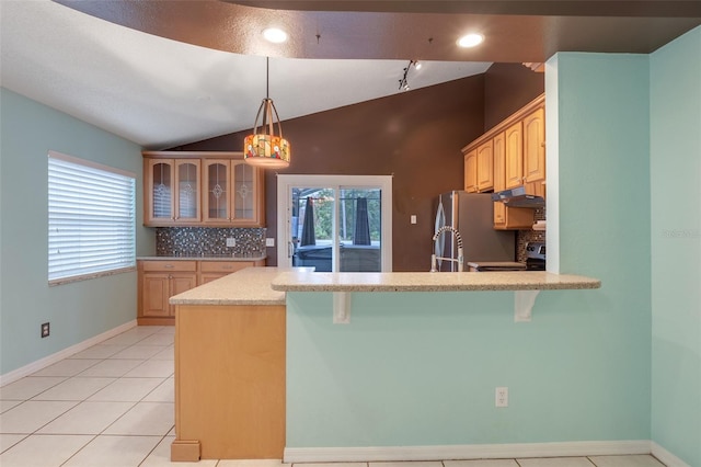 kitchen with stainless steel appliances, a breakfast bar area, decorative backsplash, and vaulted ceiling