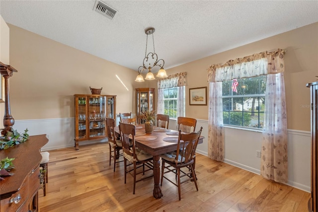 dining area with light hardwood / wood-style floors and a textured ceiling