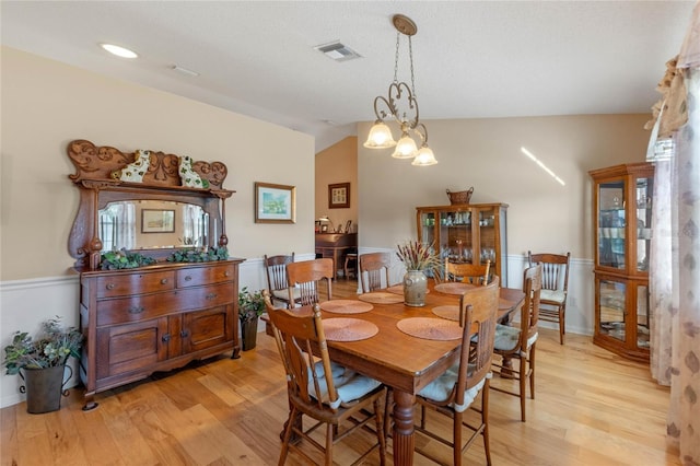 dining room featuring vaulted ceiling, light hardwood / wood-style floors, and a notable chandelier